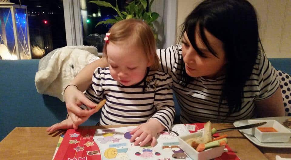 mum and daughter reading book in restaurant