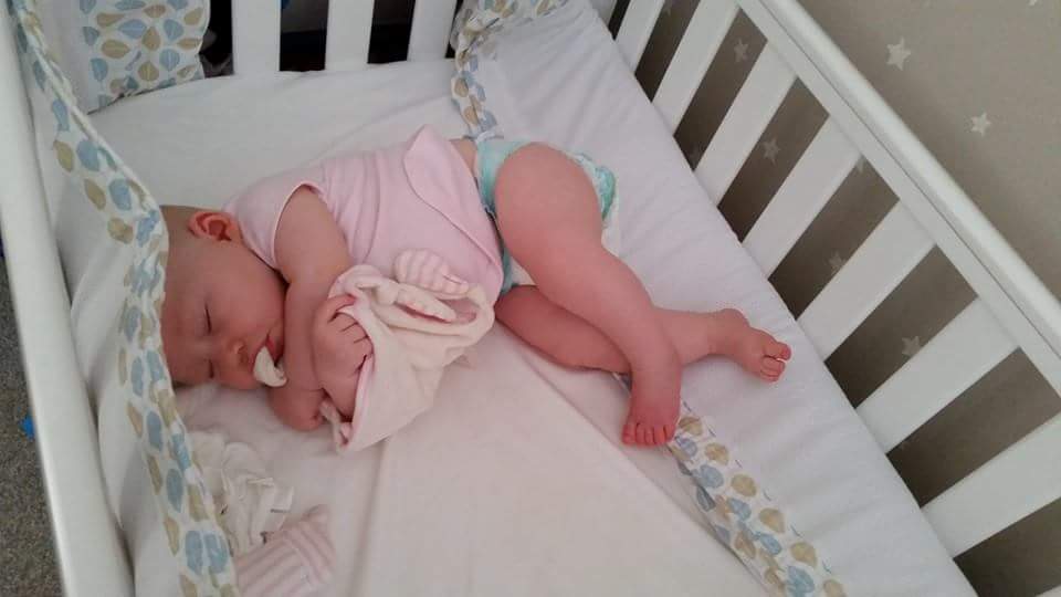 newborn baby girl asleep in cot