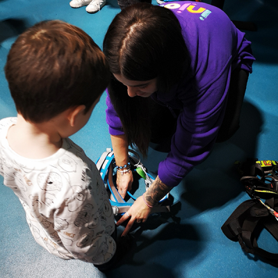 Young boy putting on climbing harness