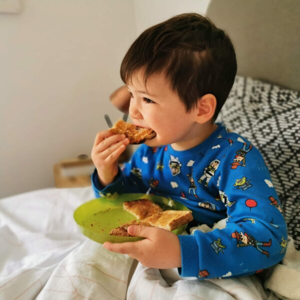 young boy eating toast in bed