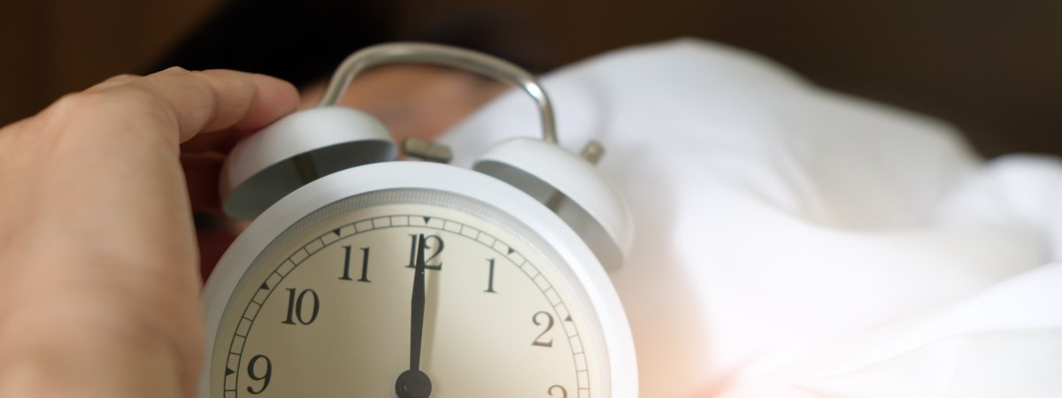 person holding an alarm clock in bed