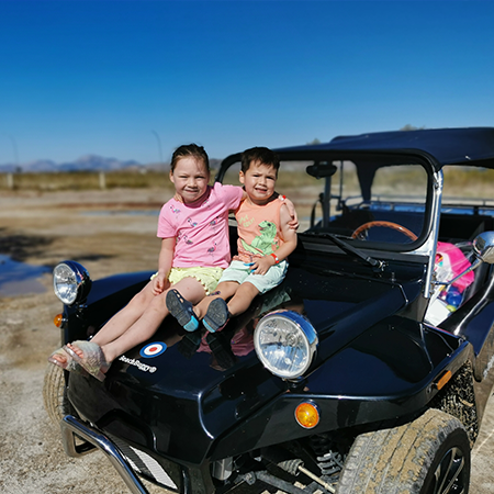 young boy and girl sat on bonnet of beach buggy