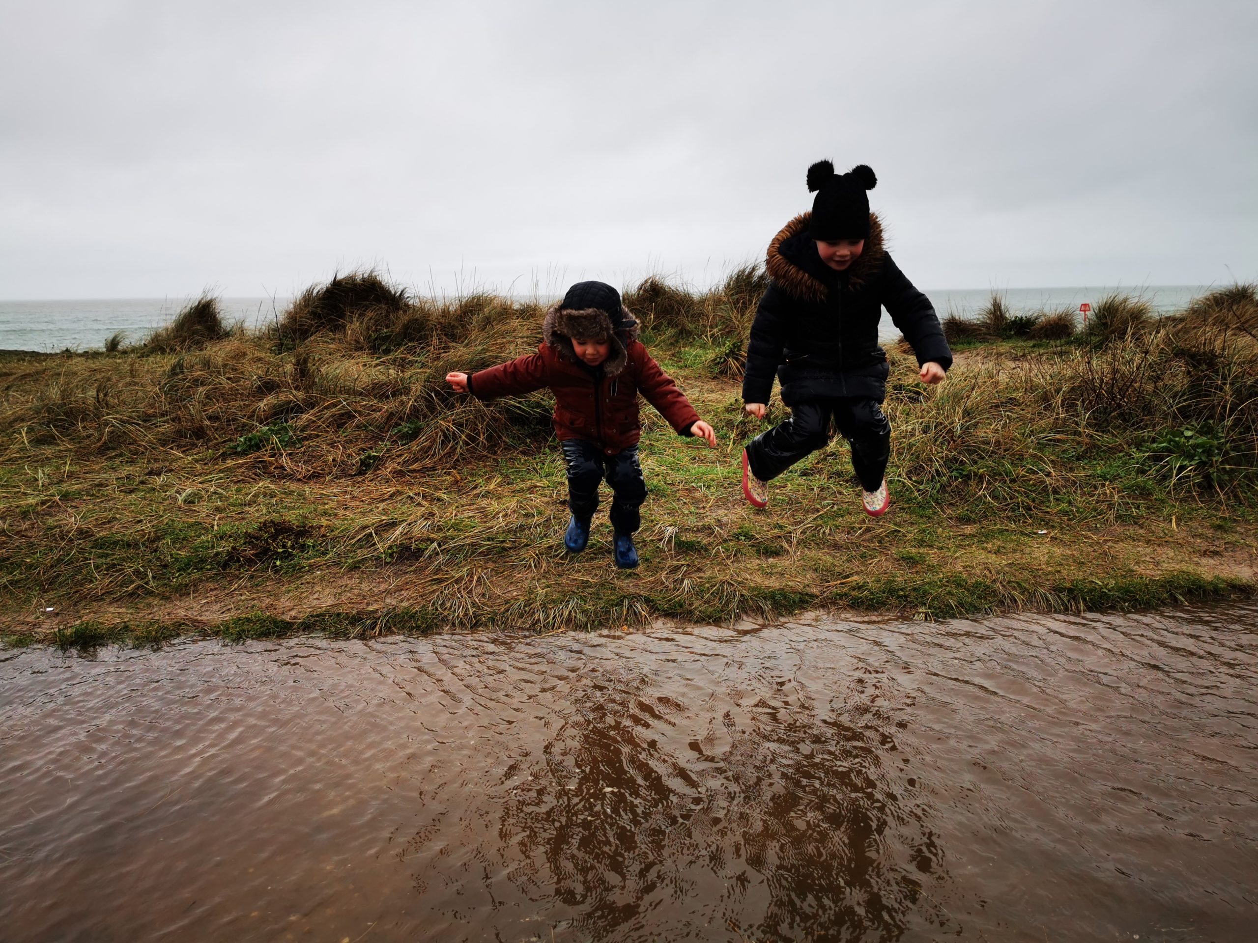 children jumping into a puddle in mid air