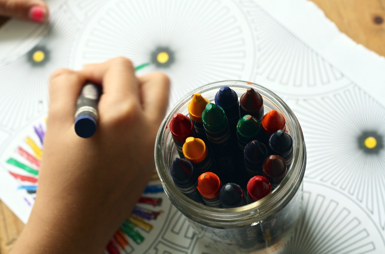 childs hand holding coloured crayon